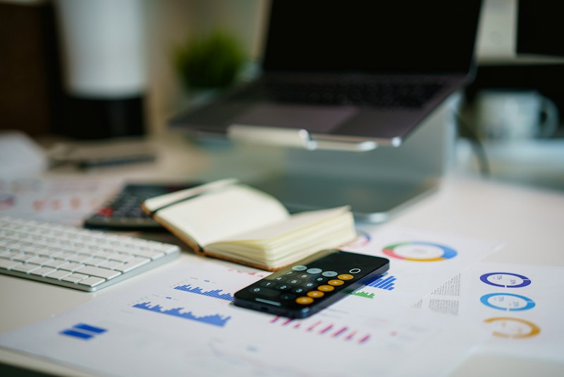 Een bureau met laptop, rekenmachine en financiële grafieken