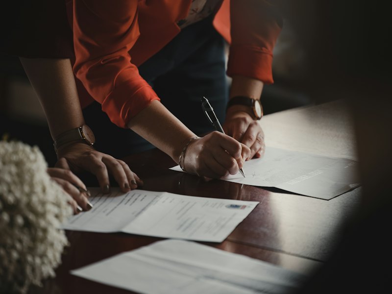 Twee mensen ondertekenen documenten aan een tafel