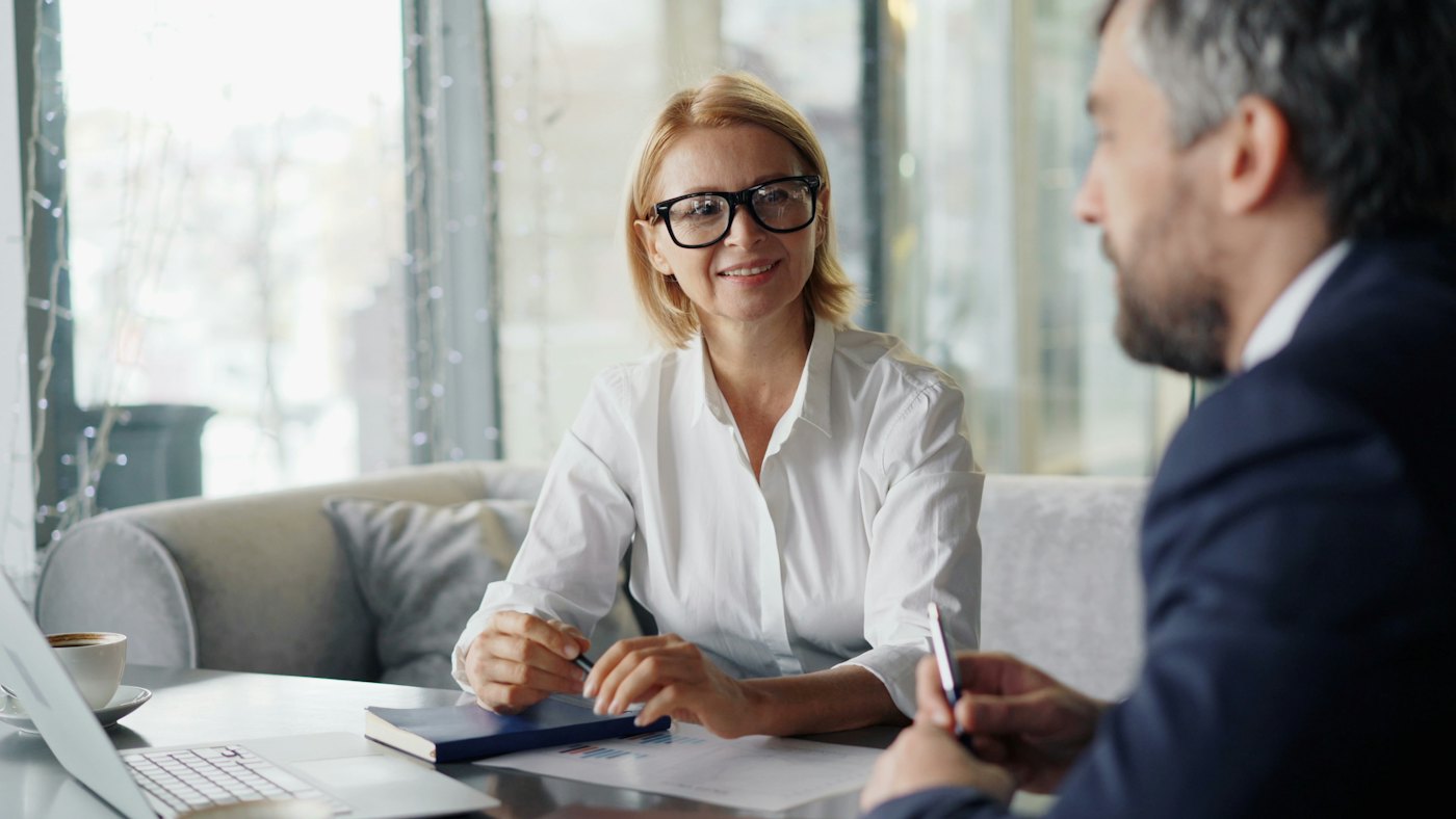 Twee collega's en een klant bespreken documenten aan een tafel